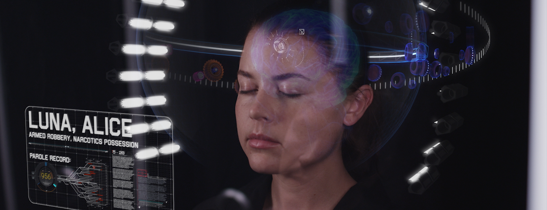 A young woman in a hibernation tank with glowing UI elements that show the status of her brain