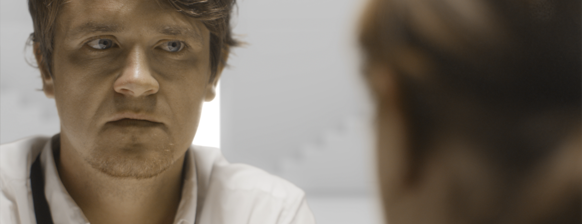 A man looks at a woman with intense discomfort as she leans across the table to confront him